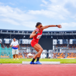 Emilia Nova melakukan gerakan tolak peluru di arena atletik