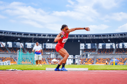 Emilia Nova melakukan gerakan tolak peluru di arena atletik
