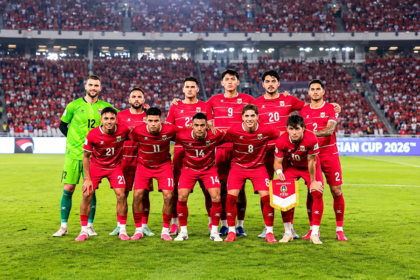 Ilustrasi 11 pemain Timnas Indonesia mengenakan seragam merah dan penjaga gawang berseragam hijau di lapangan stadion.