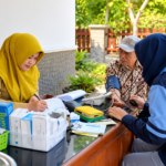 Ilustrasi tenaga kesehatan memeriksa tekanan darah warga dalam kegiatan layanan kesehatan gratis.