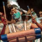 Ilustrasi penampil Festival Rontek Pacitan memainkan alat musik perkusi dengan kostum artistik dan riasan wajah berwarna biru.