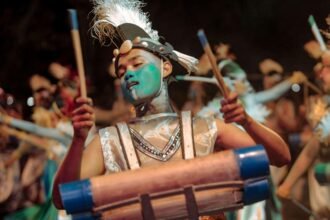 Ilustrasi penampil Festival Rontek Pacitan memainkan alat musik perkusi dengan kostum artistik dan riasan wajah berwarna biru.