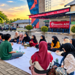 Sekelompok mahasiswa berkumpul di halaman kampus untuk berbincang dan berinteraksi sosial.