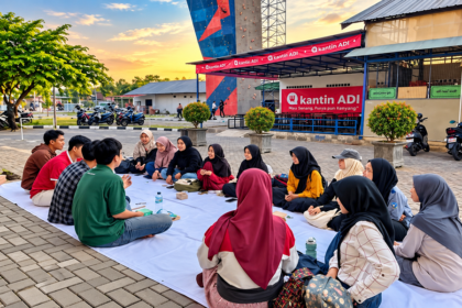 Sekelompok mahasiswa berkumpul di halaman kampus untuk berbincang dan berinteraksi sosial.