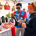 Pengunjung melihat produk kerajinan dan perhiasan UMKM di sebuah stan pameran.