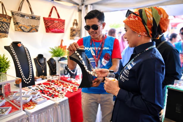 Pengunjung melihat produk kerajinan dan perhiasan UMKM di sebuah stan pameran.