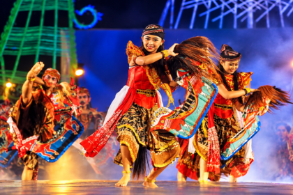 Ilustrasi penari jaran kepang mengenakan kostum tradisional merah dan emas sambil menari dengan properti kuda kepang di panggung festival.
