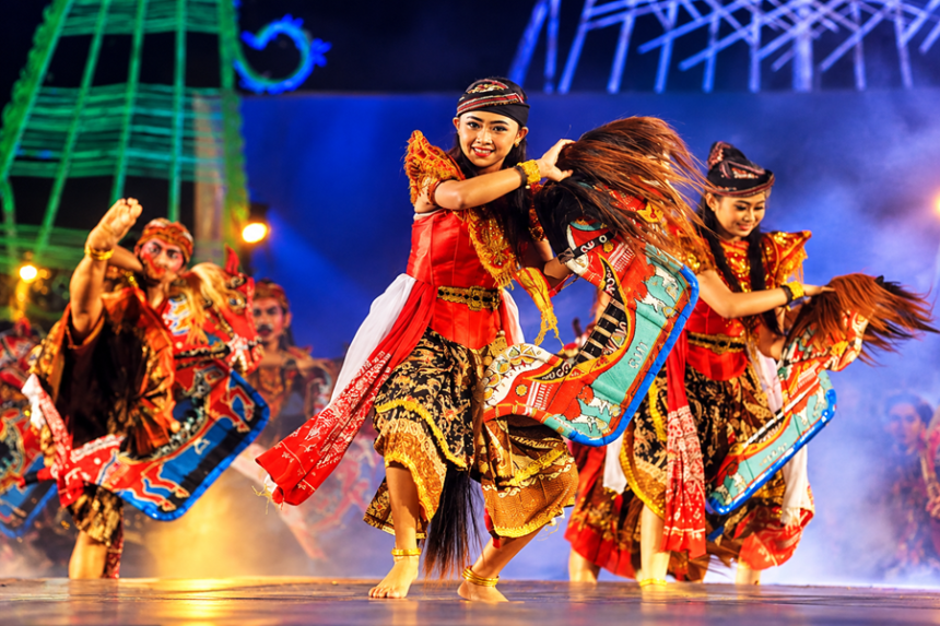 Ilustrasi penari jaran kepang mengenakan kostum tradisional merah dan emas sambil menari dengan properti kuda kepang di panggung festival.