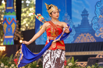 Ilustrasi penari tradisional mengenakan kostum merah berhias emas, mahkota, kain batik, dan selendang biru dalam pertunjukan seni budaya.