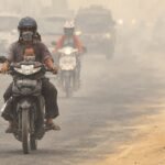 Ilustrasi polusi udara dan kabut asap di jalan raya yang mengganggu jarak pandang pengendara sepeda motor.