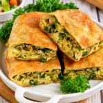 Martabak telur goreng berwarna keemasan dengan isian telur dan daun bawang, dipotong menjadi beberapa bagian.