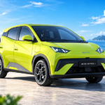Ilustrasi mobil listrik BYD Atto 1 warna hijau lime dengan desain kompak modern di tepi pantai.
