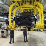 Proses perakitan mobil di pabrik otomotif modern dengan bantuan mesin dan pekerja.
