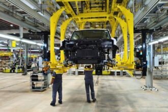 Proses perakitan mobil di pabrik otomotif modern dengan bantuan mesin dan pekerja.