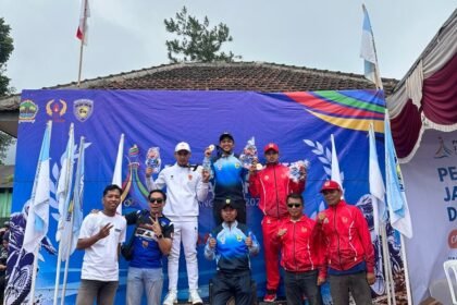 Atlet berdiri di podium juara bersama tim pendukung dalam kejuaraan olahraga