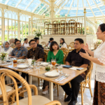 Foto ilustrasi seorang perempuan berbicara di hadapan peserta pertemuan formal di restoran.